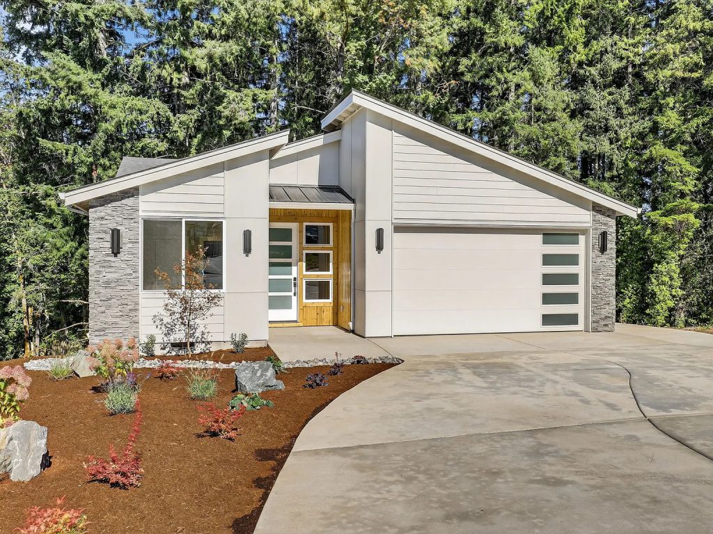 Home exterior with angular roofline, stone accents, and a wooded backdrop