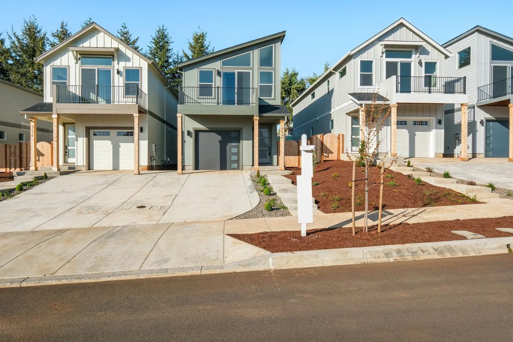 Street view of homes with upper balconies and individual garages